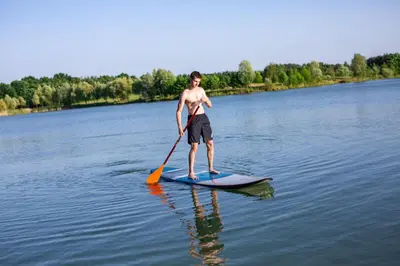 a man standing on a paddle board in the water at RESORT SALIXA u Poděbrad in Poděbrady