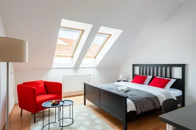 a bedroom with a bed and a red chair at 2-level apartment with large balcony in Prague