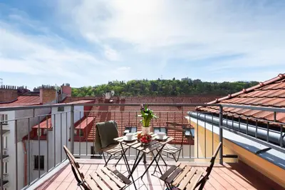 a balcony with a table and chairs on a roof at 2-level apartment with large balcony in Prague