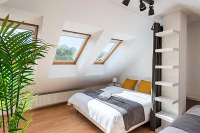 a bedroom with a bed and two windows at 2-level apartment with large balcony in Prague