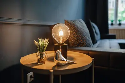 a table with a lamp and a vase with flowers on it at Royal Heritage Apartments - City Centre in Prague