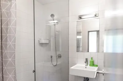 a white bathroom with a shower and a sink at Prague Camping Dzban in Prague