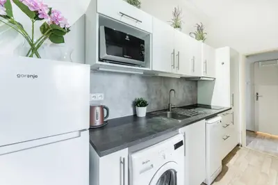 a kitchen with white cabinets and a washer and dryer at La Terrasse Apartment Prague center in Prague
