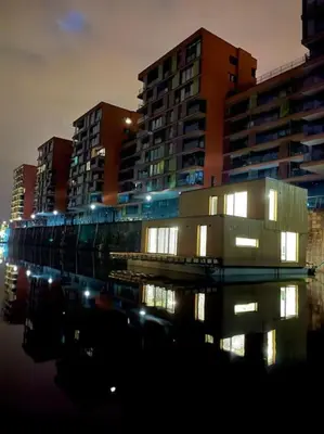 a building with lights in the water in front of buildings at One of the kind Prague Houseboat Experience +BOAT in Prague