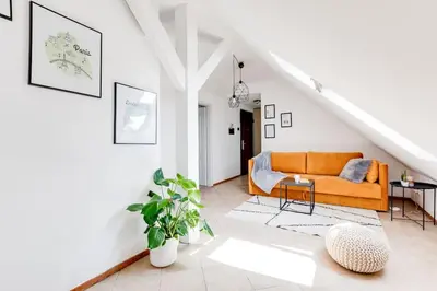 an orange couch in a white living room at Cozy & Quiet Center Attic with Castle view - vtuB in Prague