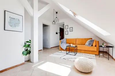 a living room with an orange couch in a attic at Cozy & Quiet Center Attic with Castle view - vtuB in Prague