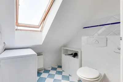 a white bathroom with a toilet and a window at Cozy & Quiet Center Attic with Castle view - vtuB in Prague