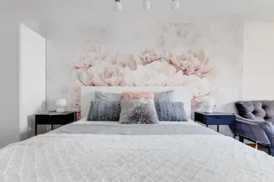 a bedroom with a large white bed with flowers on the wall at Cozy & Quiet Center Attic with Castle view - vtuB in Prague