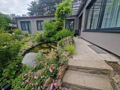 a garden with flowers and a pond in front of a house at Relax apartmán Pod Javorem in Kladno