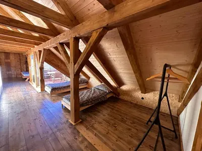 an attic with two beds in a room with wooden ceilings at Farma Bláto - Apartmány Sýpka a glamping in Uhlířské Janovice