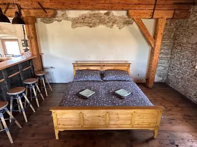 a bedroom with a wooden bed in a room with stools at Farma Bláto - Apartmány Sýpka a glamping in Uhlířské Janovice