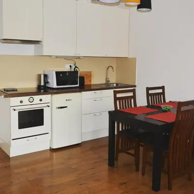 a kitchen with white cabinets and a table with a microwave at MM Apartment Argentinska in Prague