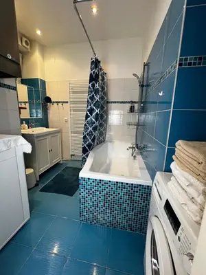 a bathroom with a tub and a washing machine at MM Apartment Argentinska in Prague