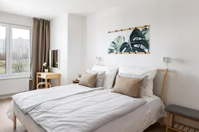 a white bedroom with a large bed and a window at Stay2gether Japandi Homestay for 4 - Metro B Luka in Prague