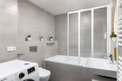 a bathroom with a tub and a toilet and a sink at Stay2gether Japandi Homestay for 4 - Metro B Luka in Prague