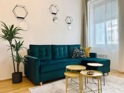 a living room with a blue couch and two tables at Stylish retreat in a lively area in Prague