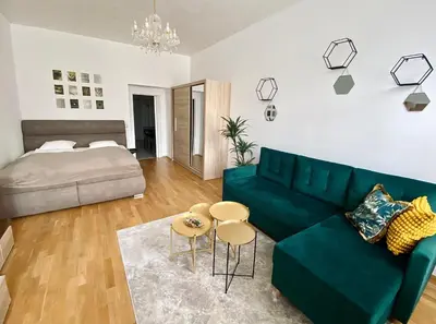 a living room with a green couch and a bed at Stylish retreat in a lively area in Prague