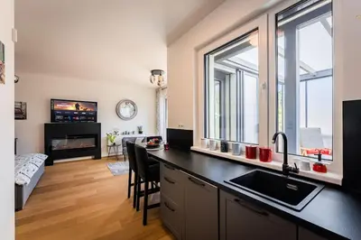a kitchen with a black counter top and a living room at Romantic wellness apartment in Prague