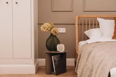 a vase with flowers on a table next to a bed at Stylish new apartment in Prague with A/C in Prague
