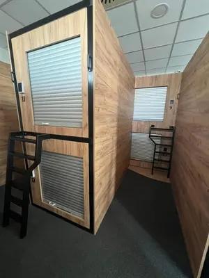 a room with two large windows and a ladder at Like a Hostel Prague in Prague