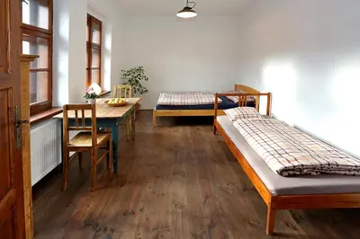 a room with two beds and a table and a dining room at Penzion U Lasíků in Únětice
