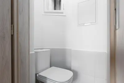 a white bathroom with a toilet and a window at Apartment near the subway with a terrace in Prague
