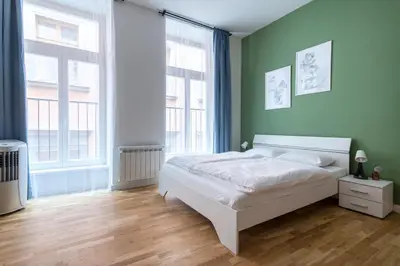 a bedroom with a white bed and two windows at City Haven Apartments in Prague