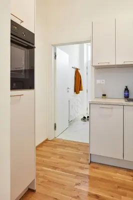 a kitchen with white cabinets and a wooden floor at Prague Days - Studio with Outdoor Seating close to Vyšehrad in Prague