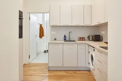 a kitchen with white cabinets and a washer and dryer at Prague Days - Studio with Outdoor Seating close to Vyšehrad in Prague
