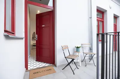 a red door on a white building with two chairs at Negrelli Residence - main BUS station in Prague