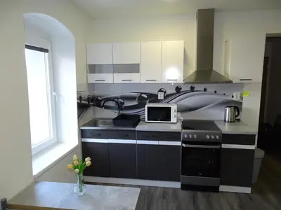 a kitchen with a sink and a stove with a microwave at Apartmán Nebužely in Nebužely