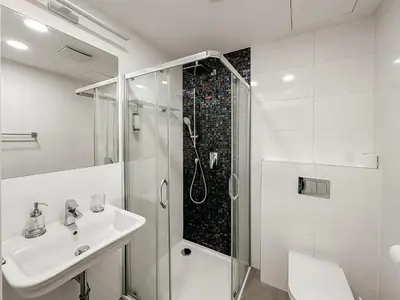 a white bathroom with a shower and a sink at ELSO Muzeum apartments in Prague