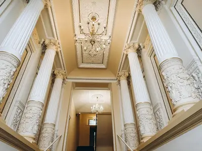 a hallway with white columns and a chandelier at ELSO Muzeum apartments in Prague