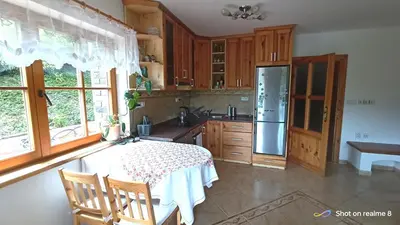 a kitchen with wooden cabinets and a table and a refrigerator at Apartmán Srubík in Čisovice