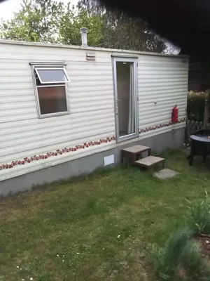 a white caravan with a window and stairs in a yard at Mobilní dům Venda in Hradištko