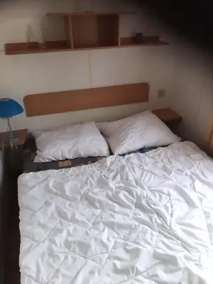 a bed with white sheets and pillows on it at Mobilní dům Venda in Hradištko