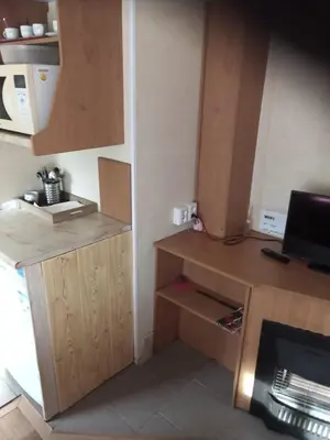 a small kitchen with wooden cabinets and a refrigerator at Mobilní dům Venda in Hradištko
