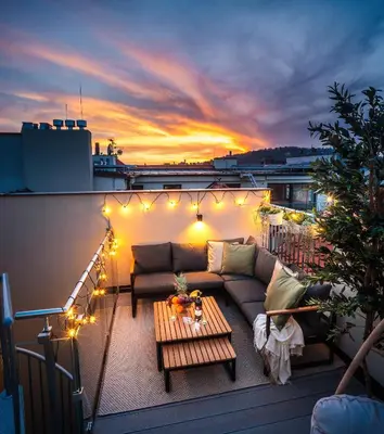 a rooftop patio with a couch and a table with lights at 3BR AC Heaven of Harmony LUXPenthouse Theater view in Prague
