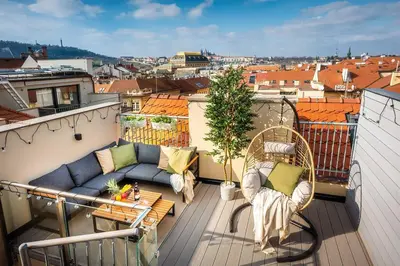 a balcony with a couch and chairs on a roof at 3BR AC Heaven of Harmony LUXPenthouse Theater view in Prague