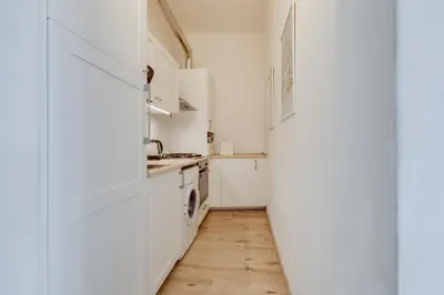 a kitchen with white cabinets and a wooden floor at Romantic apartment by the park - uaka7 in Prague
