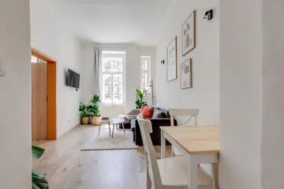 a living room with white walls and a table and chairs at Romantic apartment by the park - uaka7 in Prague