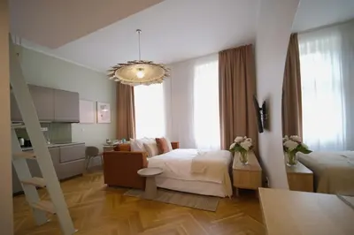 a bedroom with two beds and a kitchen and a chandelier at Luxemi Apartments I City Center Premium Studio in Prague