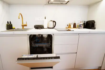 a dishwasher in a white kitchen with a sink at Luxemi Apartments I City Center Premium Studio in Prague