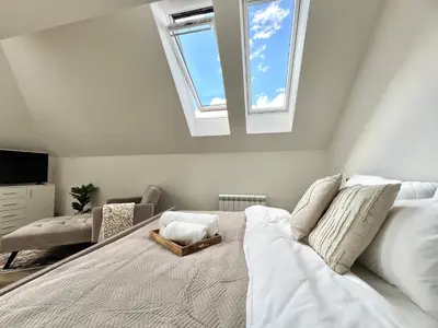 a bedroom with a large white bed with a skylight at Treetess City Centre Prague Apartments in Prague