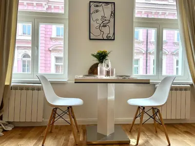 a table and two chairs in a room with windows at Treetess City Centre Prague Apartments in Prague