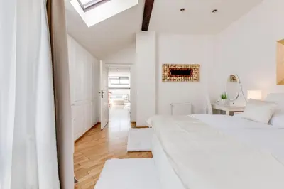 two beds in a white bedroom with a skylight at Wenceslas Square Royal Apartments in Prague