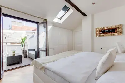 a white bedroom with a bed and a large window at Wenceslas Square Royal Apartments in Prague