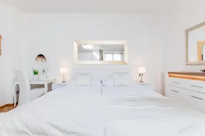 a white bedroom with a large bed and a desk at Wenceslas Square Royal Apartments in Prague