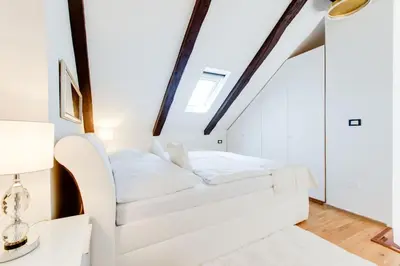 a white bed in a white room with a window at Wenceslas Square Royal Apartments in Prague