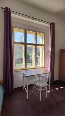 a table and a chair in a room with a window at Villa Lobkovice: Gemütliches Gästehaus am Schloss in Lobkovice